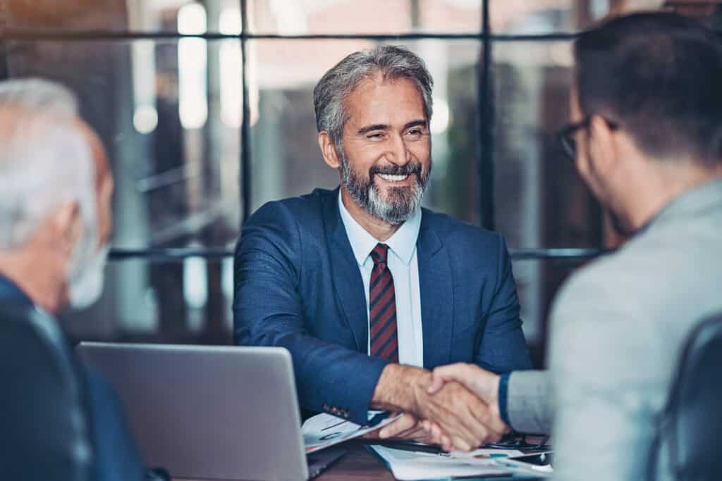 mature executive coaching shaking the hand of a business man