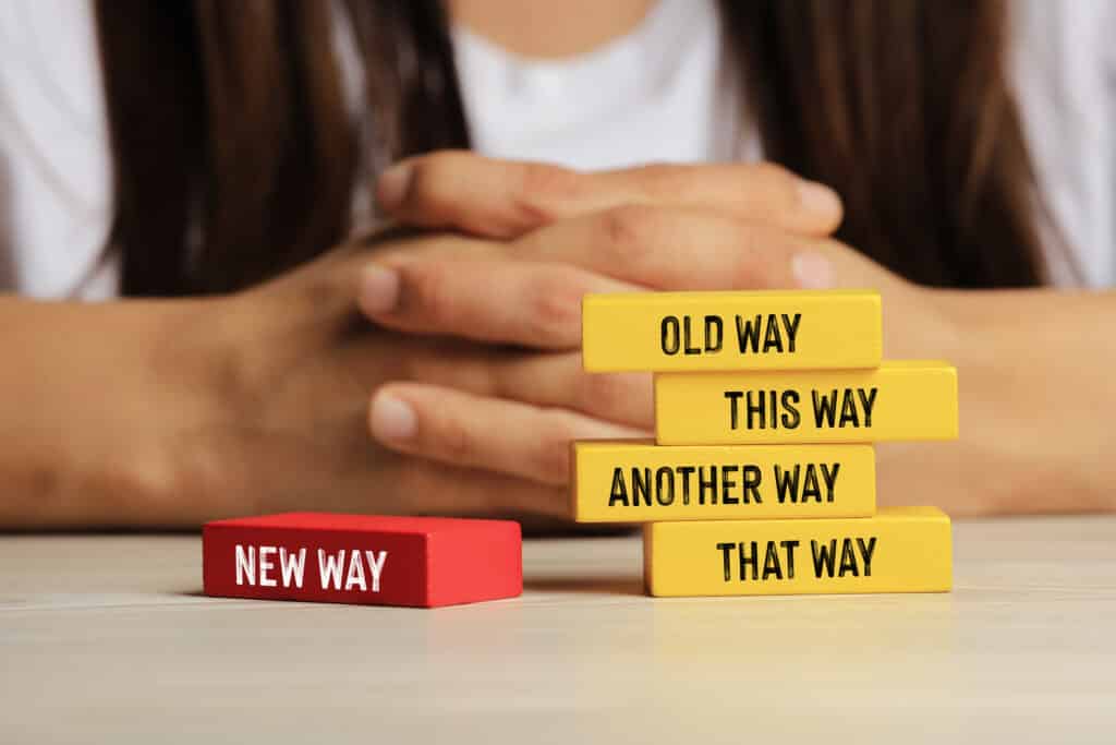 A close up of blocks featuring different directions to go in with someone sitting behind the blocks.