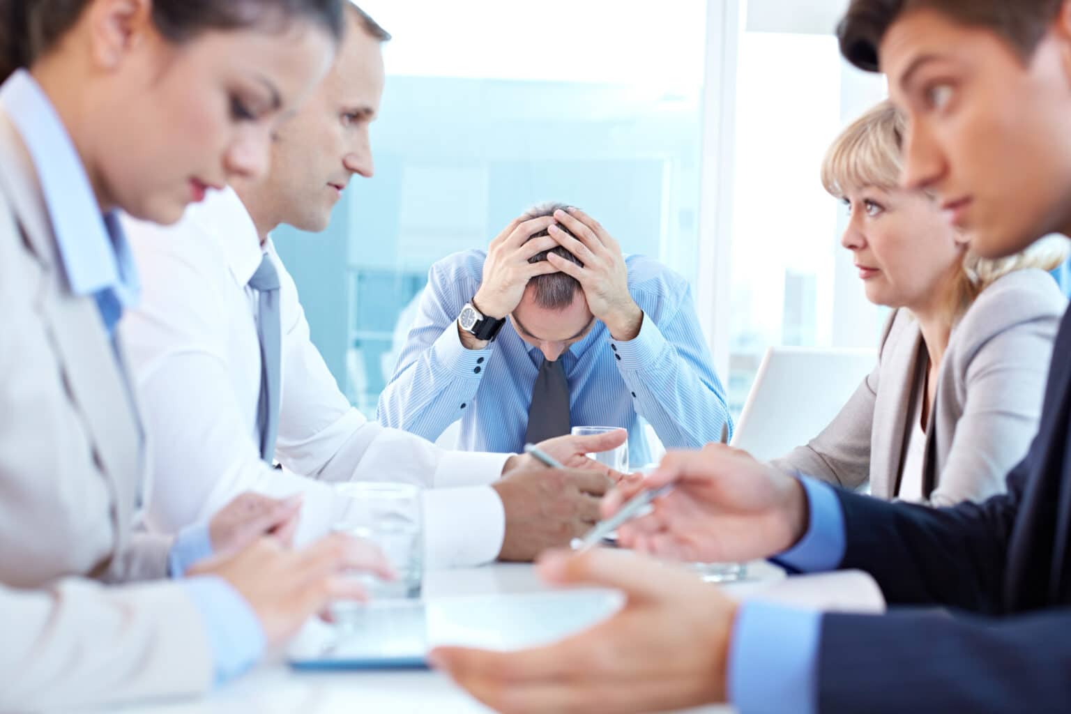 Stressed CEO sitting at the head of table at staff meeting