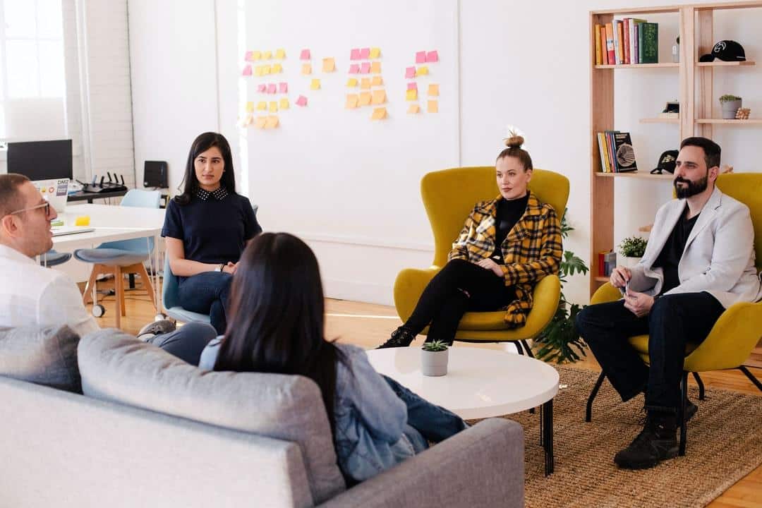 A leadership team sitting together discussing the business in a group huddle