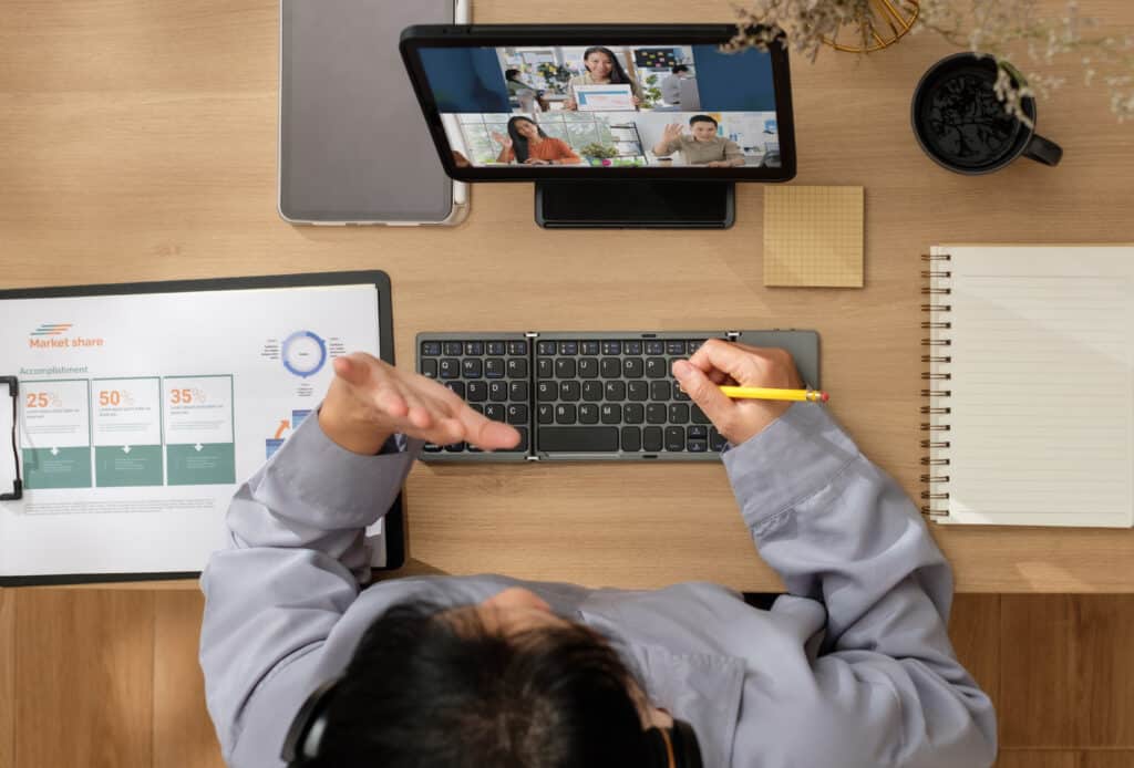 asian woman waving greeting with colleagues during a video conference