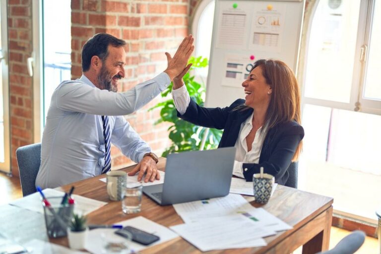 an executive wellness coach giving a high five to her client at a work table