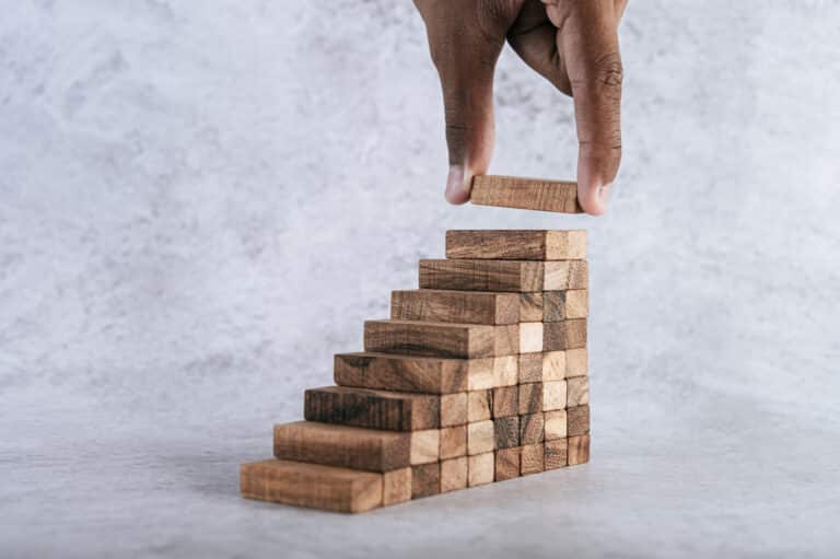 Business scalability concept with image of hand stacking wooden blocks creating business growth concept