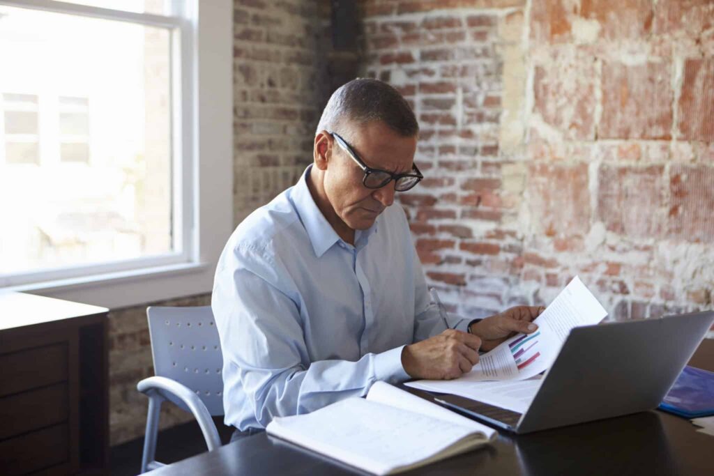 Mature COO Working On Laptop In a Boardroom