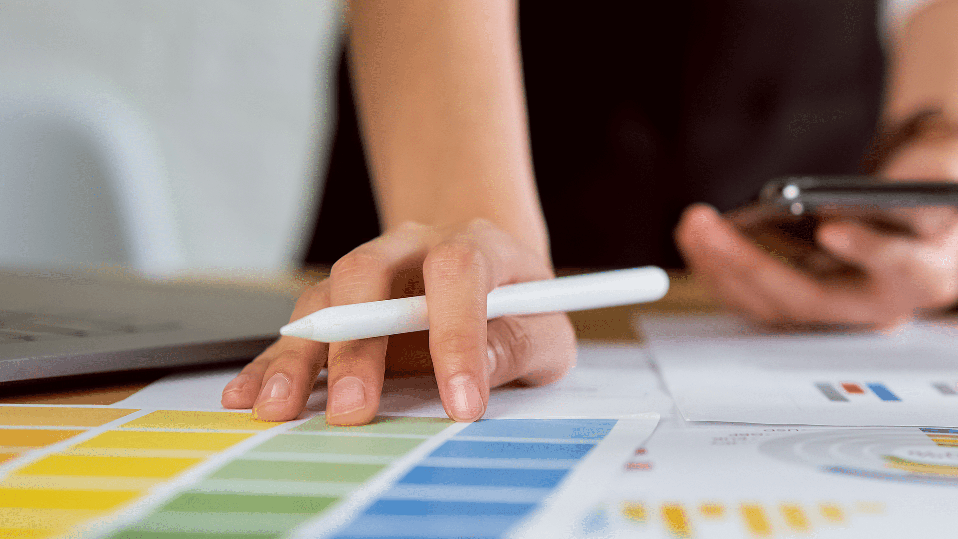 Professional reviewing color swatches and marketing charts with a smartphone, illustrating fractional CMO strategy planning.