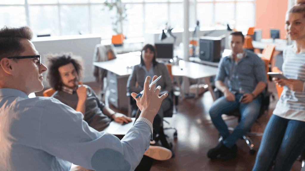 A group of professionals participating in a leadership coaching session in a modern office, engaged in interactive discussion about business strategy.