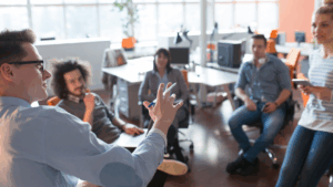 A group of professionals participating in a leadership coaching session in a modern office, engaged in interactive discussion about business strategy.