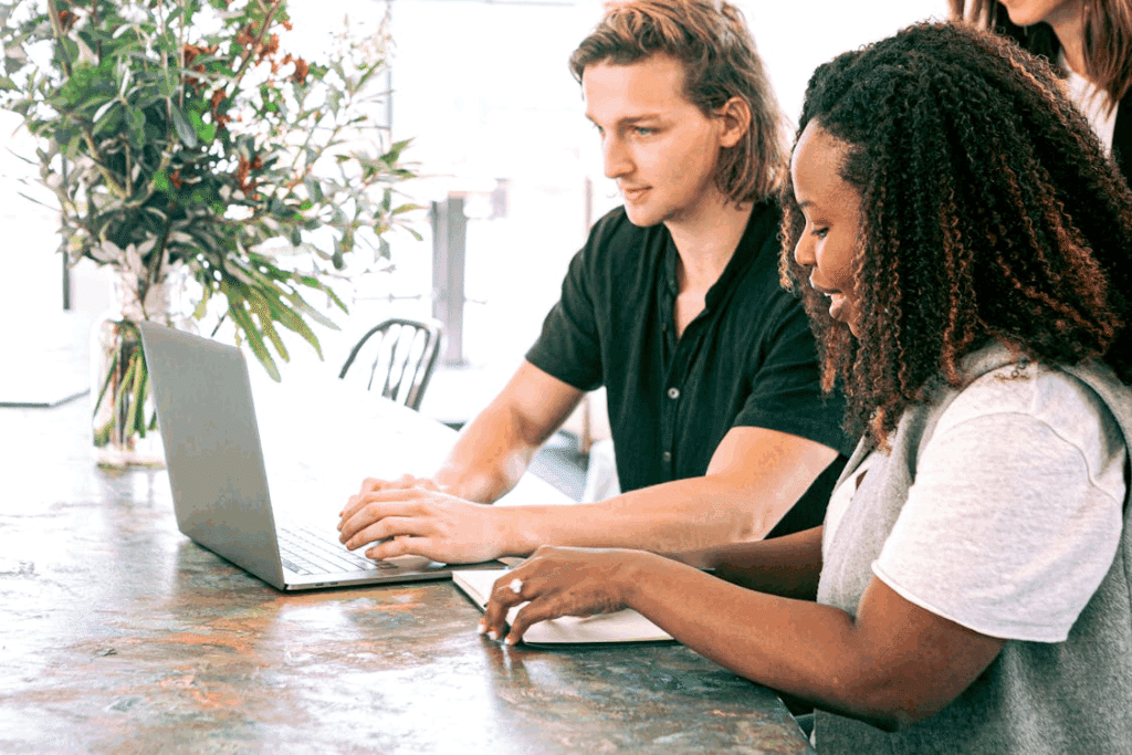 Two people employing business coaching techniques at work in front of a laptop computer.